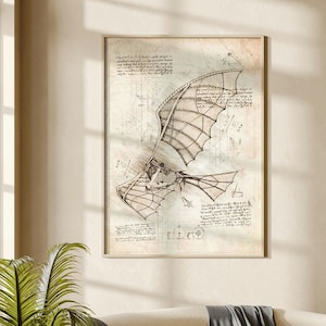 May include: A framed wall art print featuring a detailed technical sketch of a mechanical flying machine with wings, rendered in black ink on a textured, aged parchment-style background with handwritten notes and geometric diagrams.