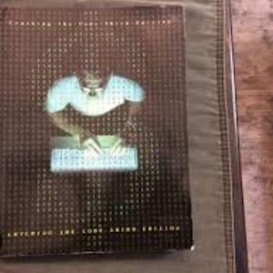 May include: A book cover with a brown background and a person typing on a keyboard. The text on the cover reads "Cracking the Code: Sixth Edition".