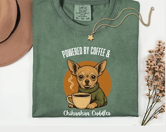 May include: Moss green t-shirt with a graphic of a Chihuahua dog holding a coffee cup. The text reads "Powered by Coffee & Chihuahua Cuddles." A gold star pendant hangs from a gold chain. The shirt is size XL-TG-EG.
