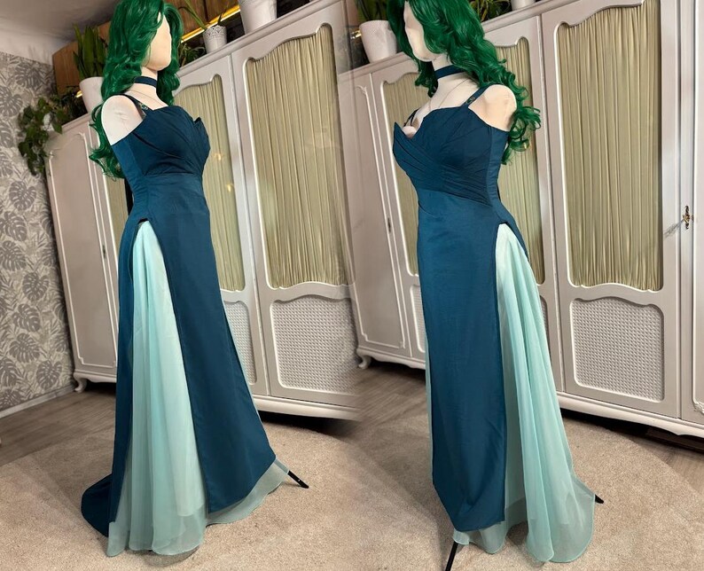 Puede incluir: Un vestido de fiesta de color verde azulado con una abertura alta que revela una capa inferior azul claro. El vestido presenta un escote coraz&oacute;n y tirantes finos. El vestido se exhibe en un maniqu&iacute; con una peluca verde y gargantilla.
