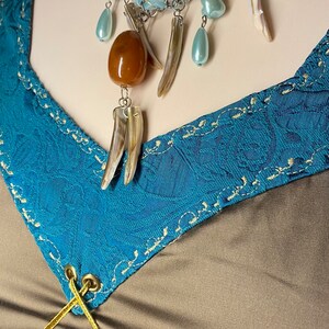 May include: A blue and brown necklace with a variety of beads and charms, including a large amber bead, a shell pendant, and several smaller blue beads.