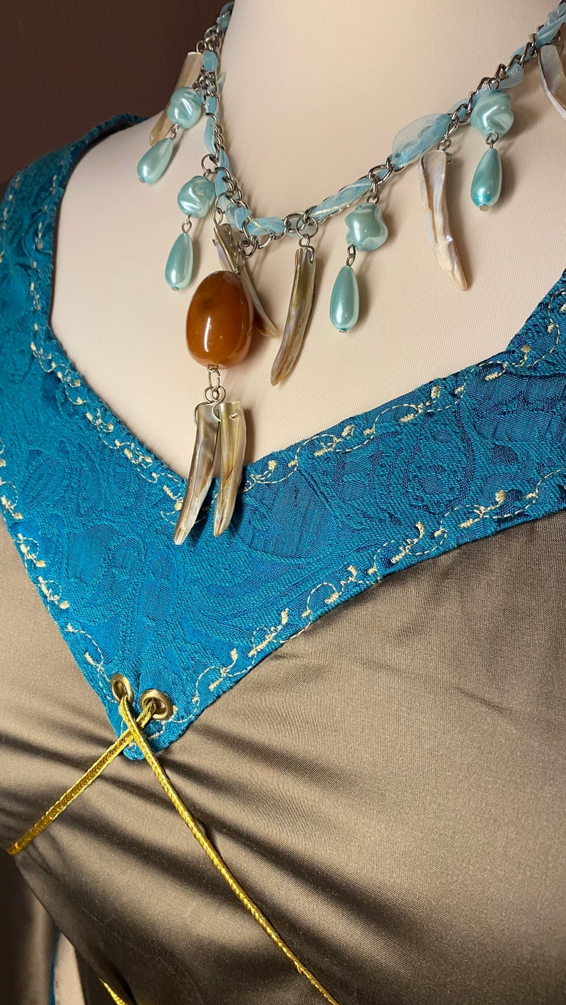 May include: A blue and brown necklace with a variety of beads and charms, including a large amber bead, a shell pendant, and several smaller blue beads.