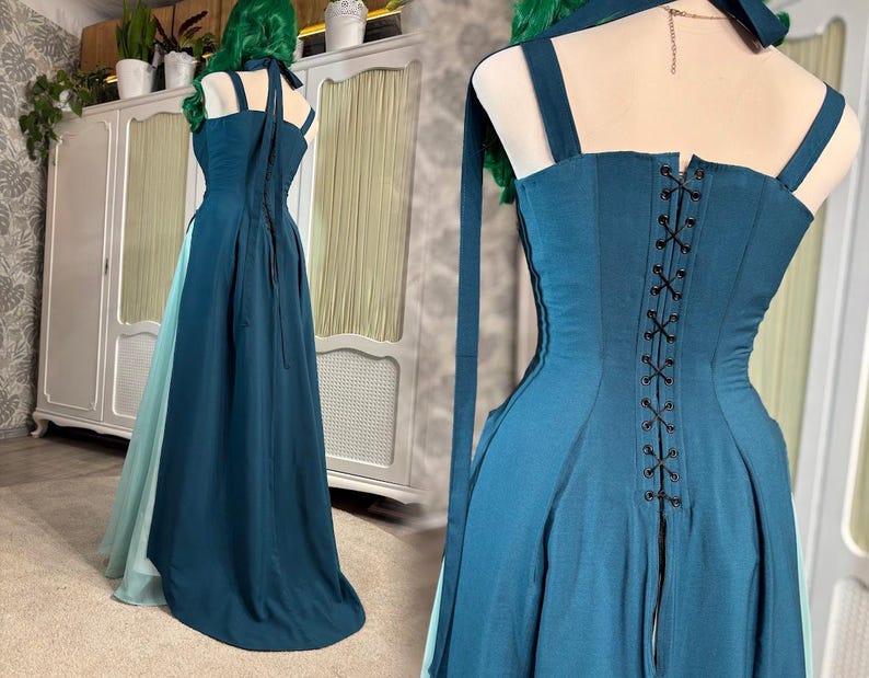 Puede incluir: Un vestido de fiesta de color verde azulado con un corpi&ntilde;o estilo cors&eacute; y una falda fluida. El vestido presenta una espalda con cordones y tirantes finos. Se ve una tela verde azulado m&aacute;s clara debajo de la falda. El vestido tiene cuello halter y lazos largos y fluidos.