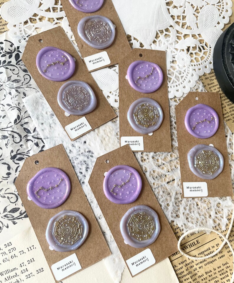 May include: Six purple wax seals with gold accents on brown card stock tags. The seals feature a constellation design and a circular design. The tags have the text "Murasaki memori" printed on them.
