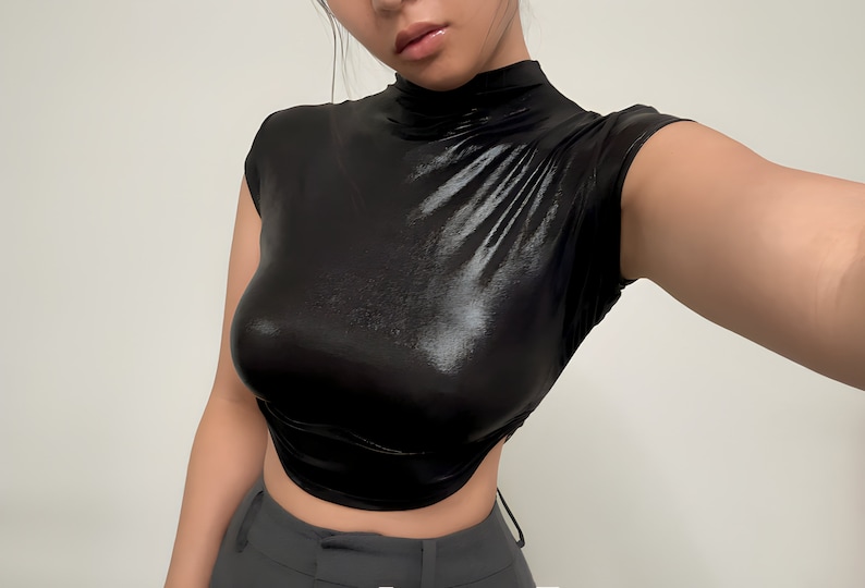 May include: A black, shiny, mock neck shirt with short sleeves. The shirt is cropped and has a fitted silhouette.