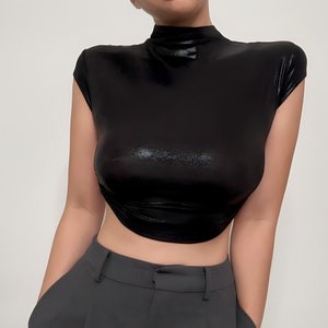 May include: A black mock neck shirt with short sleeves and a shiny finish. The shirt is cropped and has a fitted silhouette.