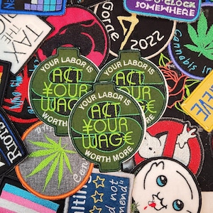 Könnte beinhalten: Eine Sammlung bunter gestickter Patches mit verschiedenen Designs, darunter ein grüner Patch mit dem Text "Act Your Wage Worth More", ein schwarzer Patch mit einem Marihuana-Blatt und ein roter Patch mit einem schwarzen Panther.