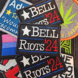 May include: Three black and white embroidered patches with a white star and the text "BELL RIOTS '24" in white and red lettering. The patches are on a black background.