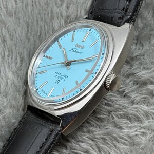 May include: A vintage Kohinoor wristwatch with a light blue face and silver case. The watch features a black leather band and the text "PARA SHOCK 17 JEWELS". The watch is marked "MADE IN INDIA".