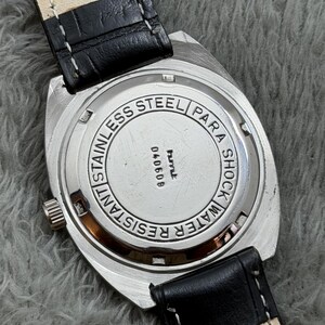 May include: A stainless steel watch with a black leather band. The watch face is silver with the words "Stainless Steel", "Water Resistant", and "Para Shock" engraved. The watch band is black leather with white stitching.