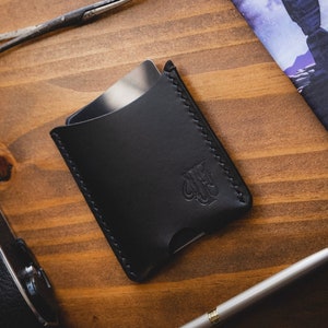 Cartera minimalista en vertical hecha en cuero Pueblo en negro, cosida a mano con hilo negro. The Lone Wolf.