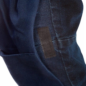 May include: Close-up of a dark blue denim jacket with a black patch on the sleeve.