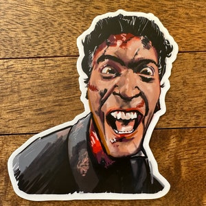 May include: A sticker featuring a close-up illustration of a man with a bloody face, screaming with his mouth open, showing his teeth. He has dark hair and is wearing a dark suit.