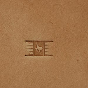 Peut inclure: Gros plan sur une surface en cuir beige avec un motif en relief. Le motif présente une forme rectangulaire avec des lignes verticales sur les côtés gauche et droit, et le contour de l'État du Texas au centre.