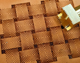 May include: A close-up of a leather stamping tool with a geometric pattern. The tool is being used to create a repeating pattern on a piece of leather.
