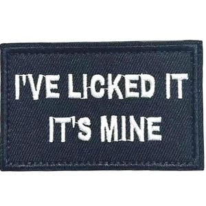 May include: A rectangular black patch with white embroidered text that reads "I'VE LICKED IT IT'S MINE". The patch has a stitched border.