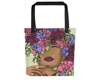 May include: A tote bag with a colorful floral design featuring a woman with brown skin and a crown of flowers. The background is a light green with a subtle pattern.