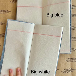 May include: Two open notebooks with white pages and red lines. The notebook on the left has the text "Big white" printed on the page. The notebook on the right has the text "Big blue" printed on the page.