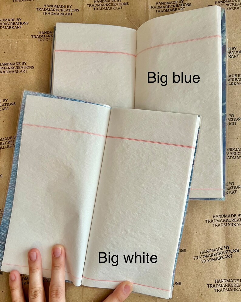 May include: Two open notebooks with white pages and red lines. The notebook on the left has the text "Big white" printed on the page. The notebook on the right has the text "Big blue" printed on the page.
