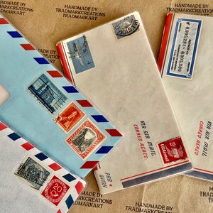 May include: Four vintage envelopes with red, white, and blue accents. The envelopes have stamps and markings in various languages, including "Via Air Mail" and "Mit Luftpost".