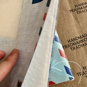 May include: A close-up of a white envelope with a blue and red patterned envelope underneath. The text "FTPOST" is visible on the white envelope. The text "HANDMAD TRADMARKC TRADMA" is visible on the brown envelope.