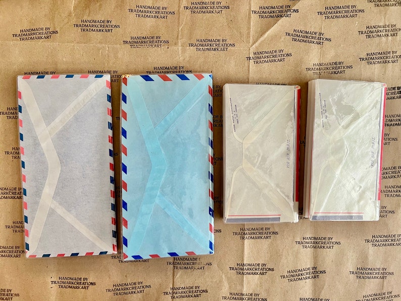 May include: A stack of five white and blue envelopes with red and blue stripes. The envelopes are made of paper and have a clear plastic window.