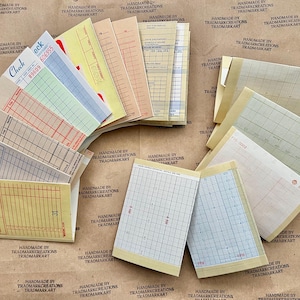 May include: A collection of vintage checkbook covers and graph paper sheets. The covers are in various colors, including yellow, blue, green, and red. The graph paper sheets are in a light beige color with blue lines.