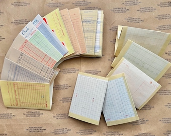 May include: A collection of vintage checkbook covers and graph paper sheets. The covers are in various colors, including yellow, blue, green, and red. The graph paper sheets are in a light beige color with blue lines.
