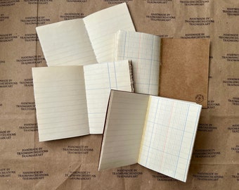 May include: A collection of small, blank notebooks with lined pages. The notebooks are closed and stacked on top of each other. The notebooks are on a brown paper surface with the text "Handmade by Trademarkcreations Trademarkart" printed on the surface.