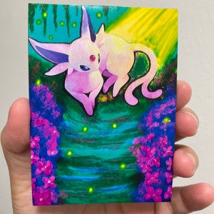 May include: A pink and purple Eevee Pokemon illustration with a red gem on its forehead. The Eevee is curled up on a green and blue background with yellow lights and pink flowers.