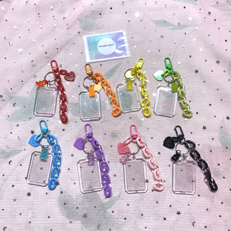 May include: Assortment of eight colorful keychains with clear plastic photo frames, each featuring a different gummy candy charm. The keychains are made with metal rings and colorful chains.
