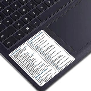 May include: A black laptop keyboard with a white sticker on the touchpad. The sticker contains a list of keyboard shortcuts and code generation commands for a coding program. The text on the sticker includes "General Shortcuts", "Code Generation Commands", "Workspace and Terminal", and "HappyPODStudio".