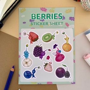 K&ouml;nnte beinhalten: Eine Sticker-Tafel mit gr&uuml;nem Hintergrund und wei&szlig;en Blumen. Die Tafel zeigt neun Sticker von Comicfiguren mit verschiedenen Fr&uuml;chten und Beeren. Die Figuren tragen alle H&uuml;te und haben unterschiedliche Gesichtsausdr&uuml;cke. Der Text "BERRIES STICKER SHEET" ist oben auf der Tafel gedruckt.