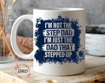 May include: White ceramic coffee mug with a blue and white design. The text on the mug reads "I'm not the step dad I'm just the dad that stepped up".