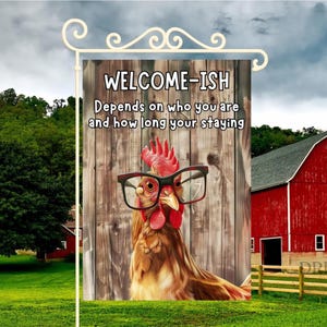 May include: A garden flag with a humorous design. The flag features a rooster wearing glasses with the text "WELCOME-ISH Depends on who you are and how long your staying." The background includes a red barn and a wooden fence.