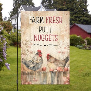 May include: A garden flag with the text "FARM FRESH BUTT NUGGETS" in black and red. The flag features two chickens, a wooden fence, and several eggs. The background has a rustic, vintage style.