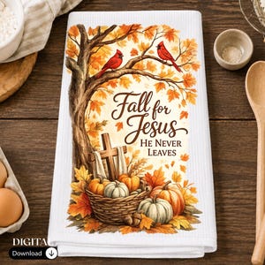 May include: A white waffle-weave kitchen towel featuring a printed autumn scene with a large tree, two red cardinals, a wooden cross, and a basket of pumpkins. The text reads Fall for Jesus He Never Leaves in a dark brown script and serif font.