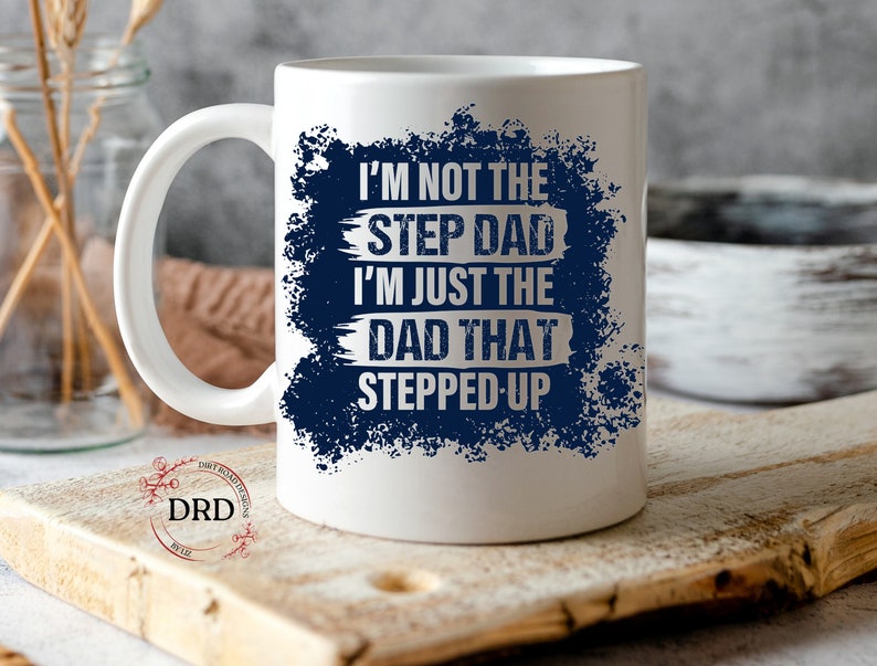 May include: White ceramic coffee mug with a blue and white design. The text on the mug reads "I'm not the step dad I'm just the dad that stepped up".