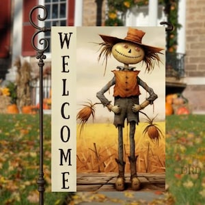 May include: A decorative garden flag featuring a scarecrow illustration. The scarecrow has a straw hat, a button-up vest, and tattered clothing. The flag reads "WELCOME" in bold, black letters. The background shows a field and a house.