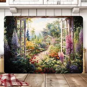 May include: Rectangular chopping board with a colourful garden scene. The image shows an open window framing a garden path with flowers, a small greenhouse, and a bright sky. The board is set on a wooden surface.
