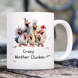 May include: White ceramic mug with a colorful cartoon image of a group of chickens. The text "Crazy Mother Cluckers" is printed on the mug.
