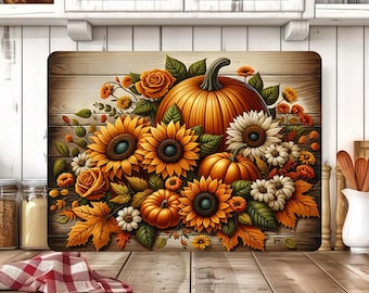 May include: A rectangular cutting board with a fall-themed design. The image features a vibrant arrangement of pumpkins, sunflowers, roses, and autumn leaves in shades of orange, yellow, and green, set against a wooden background.