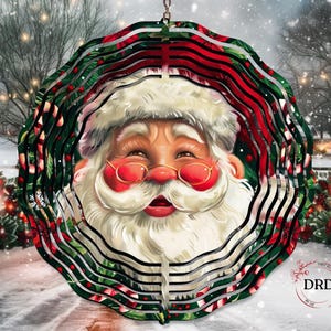 Puede incluir: Adorno navide&ntilde;o decorativo con la cara de Pap&aacute; Noel. El adorno tiene un dise&ntilde;o en capas con detalles en rojo, verde y blanco. Pap&aacute; Noel lleva gafas con montura dorada y barba blanca. El fondo muestra una escena invernal nevada.