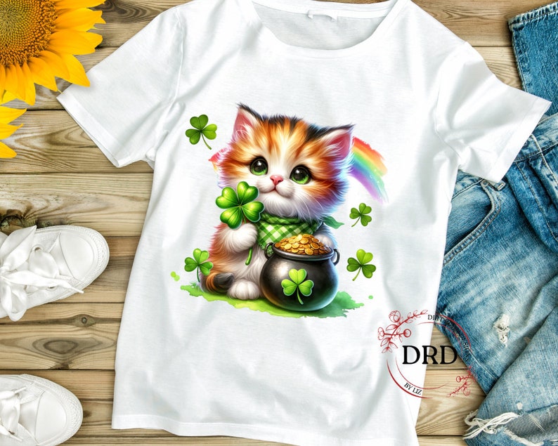 May include: White t-shirt with a cartoon image of a cute orange and white cat holding a pot of gold and a shamrock. The cat is surrounded by shamrocks and a rainbow.