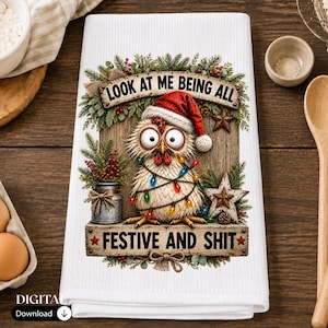 May include: A white waffle-weave kitchen towel featuring a graphic of a chicken wearing a Santa hat and wrapped in colorful Christmas lights. The design includes pine branches, berries, and the text: LOOK AT ME BEING ALL FESTIVE AND SHIT.