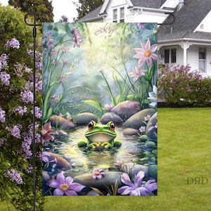 Puede incluir: Una rana verde se sienta en un arroyo rodeado de rocas y flores. El agua es clara y la rana mira al espectador. El fondo es un suave lavado de acuarela verde y azul.