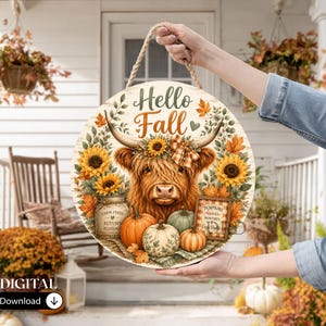 May include: A round wooden sign featuring a Highland cow illustration with the text Hello Fall, surrounded by sunflowers, pumpkins, and a mason jar. The sign includes a rope hanger and displays a plaid sign with the text Pumpkins, Leaves, Cozy Nights.