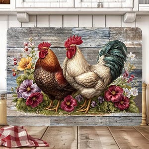 May include: Rectangular cutting board featuring a rustic design with two roosters and floral accents. The roosters have red combs and wattles, with one having brown feathers and the other white. Flowers include red, purple, and yellow blooms.