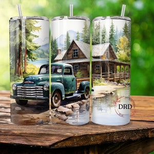 May include: A stainless steel tumbler with a watercolor design featuring a vintage green truck parked near a cabin in a forest setting. The design includes a lake and mountains, with a straw.