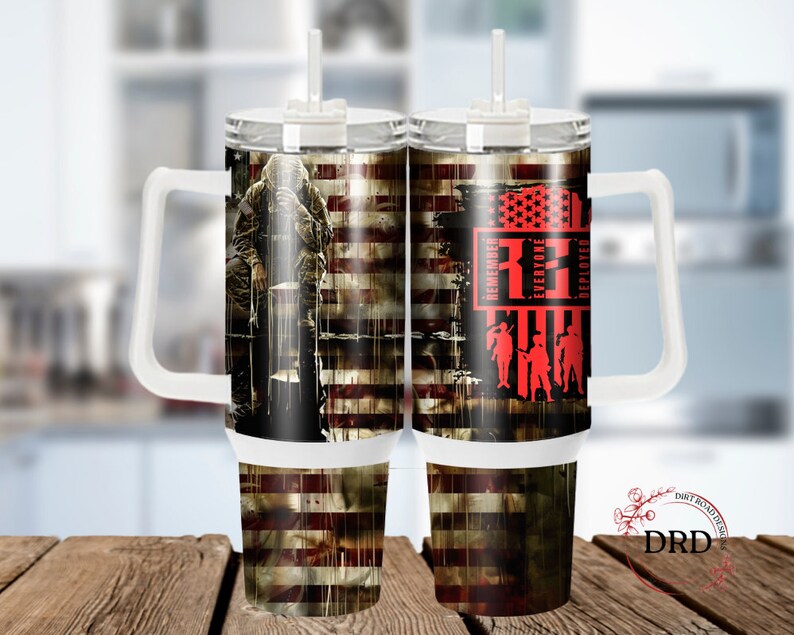 May include: A white stainless steel tumbler with a handle and a straw. The tumbler has a design of an American flag with a soldier in front of it. The text "Remember Everyone Deployed" is on the tumbler.